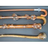 Three carved wooden walking sticks & walking stick with folding leather covered handle / seat,