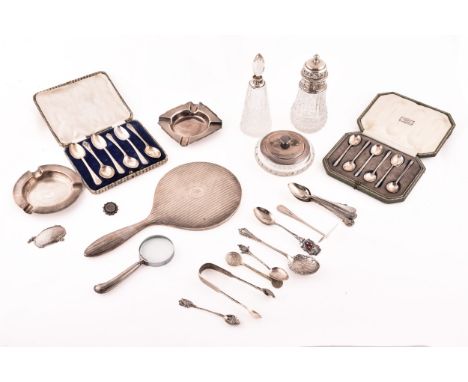 A collection of assorted silver items, including several teaspoons, sugar cube tongs, hand held mirror, silver topped glass t