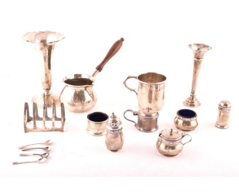 A group of assorted silver items, including a brandy pan, a silver cup, condiment sets, toast rack, and two spill vases.  Con