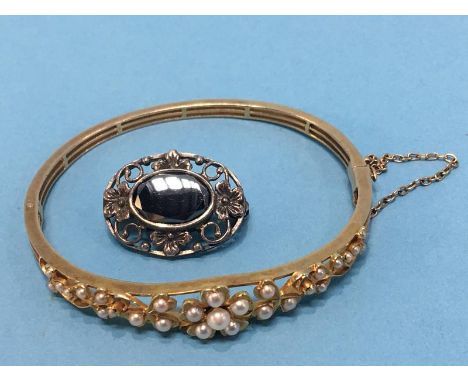 A yellow metal bracelet, mounted with seed pearls and a broochThe bangle is not hallmarkedTotal weight 13.5 grams1.74mm diame