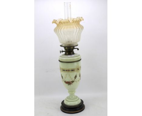 An Edwardian opaque glass oil lamp.  With frilled and etched shade above white glass body painted with swags of flowers, on s