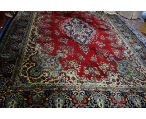 A LARGE RED GROUND CARPET with a blue border, with allover floral decoration, 297cm wide x 280cm long (approx) (plus fringes)