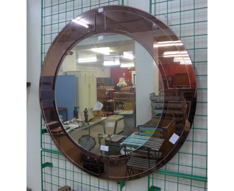 An Art Deco style peach glass circular mirror 