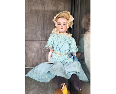 An Armand Marseille 8/OX bisque head doll with fixed blue eyes, open mouth with four teeth, straw and fabric body with bisque