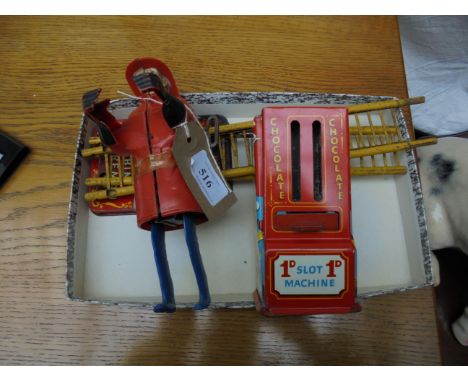 Clockwork Fireman with accessories, together with a 1d penny chocolate slot machine 