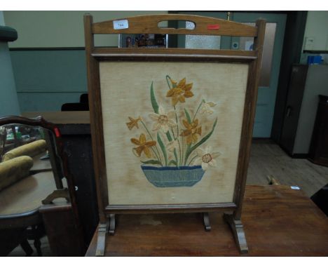 Oak framed fire screen, the needlework central panel decorated bowl of coloured flowers