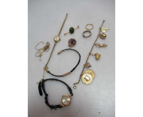 A charm bracelet tested as 9ct gold with assorted charms, an amethyst brooch stamped '9CT', a scarob brooch stamped '9C', a b