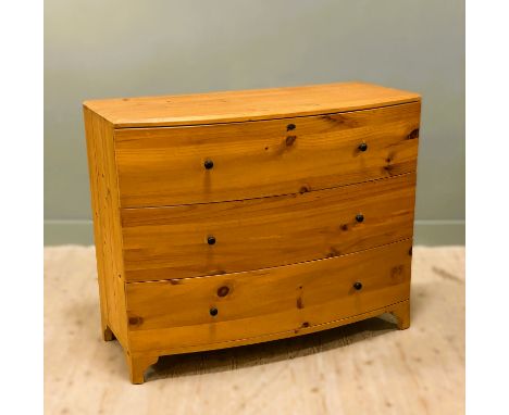A modern pitch pine bowfront chest fitted three long drawers, on bracket feet (h.98cm x l.122cm x d.53cm)