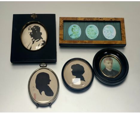 A collection of miniature portraits comprising a black silhouette portrait within a black wooden frame with an acorn drop dec