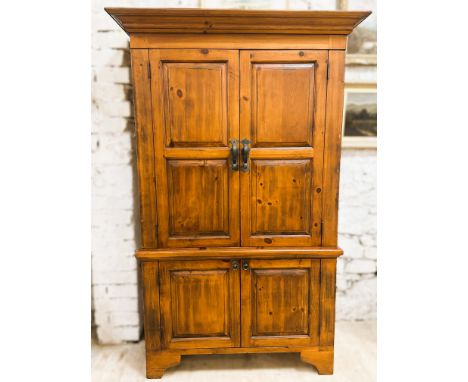 A large Mexican pine cabinet, with a moulded cornice above a apir of panelled doors opening to reveal a low shelf, above a pa