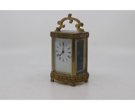 A French gilt brass carriage clock, early 20th Century, the serpentine five-glass case with moulded scrollwork and scroll han