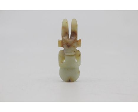 A Chinese pale celadon and russet jade amulet in the neolithic style, Qing Dynasty, of semi-figural form, the mask head with 