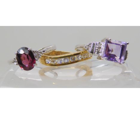 A 9ct white gold rhodolite garnet and white topaz ring size N, a 9ct amethyst and white topaz ring size N1/2, and a 9ct rainb