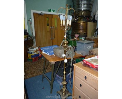 A heavy brass standard lamp with four bulb fittings, standing on three claw style feet and with three cherub faces below the 