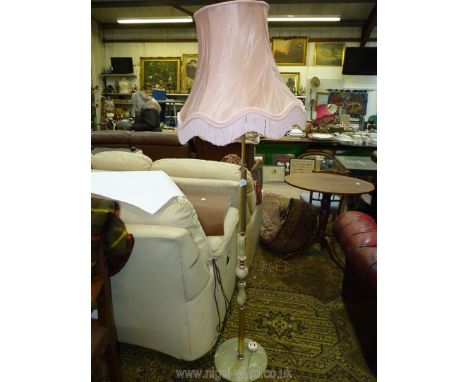 A brass and onyx standard lamp with pink fringed shade.