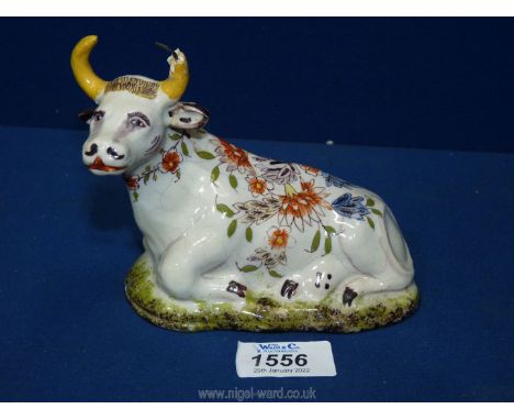 An antique model of a seated cow in Delft style, restoration to horns, 5'' tall