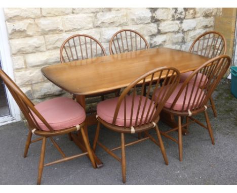 An Ercol 'Autumn' Gold Dining Table with six Latimer spindle back dining chairs.