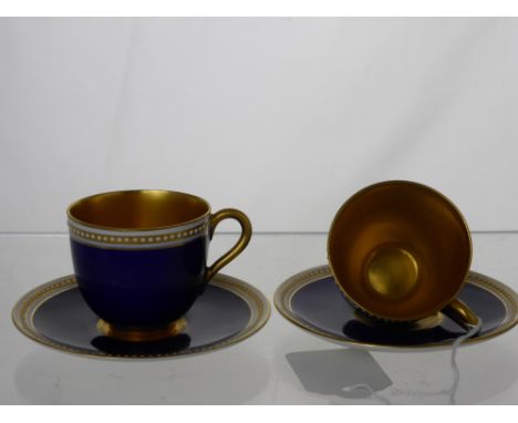 A Pair of Royal Worcester Factory Demi-Tas Cups and Saucers, in cobalt blue with white beaded decoration and gilded interior 