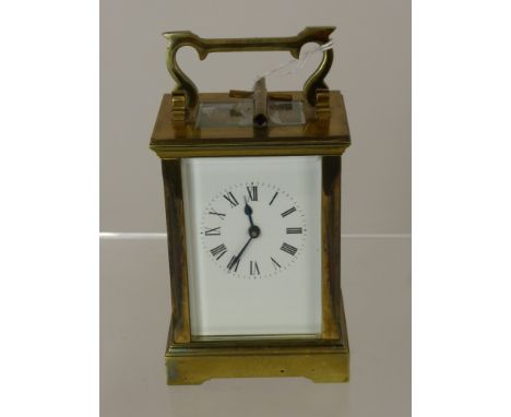 A Brass Carriage Clock with white enamel face and Roman dial, movement stamped A.C.G., approx 15 x 8 cms including handle, wi