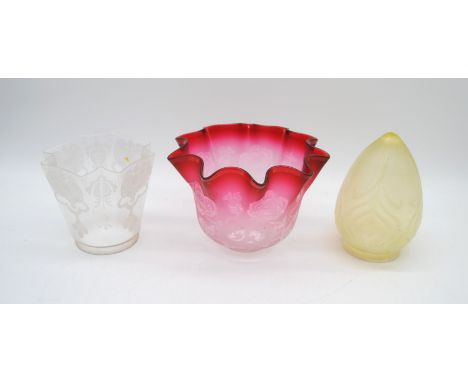 A cranberry glass oil lamp shade, along with two other glass lamp shades
