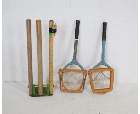 A set of spring loaded cricket stumps on cast iron base, along with a vintage Slazenger tennis racket and a Dunlop tennis rac