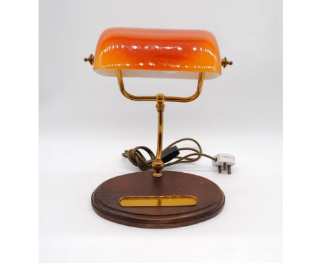 A banker's lamp with orange shade