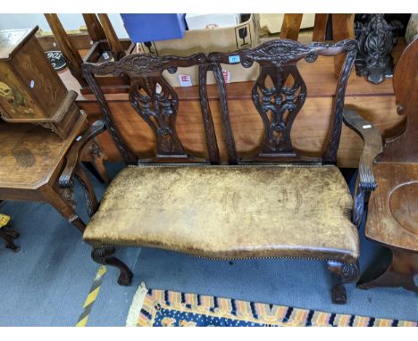 A 1920's mahogany Chippendale style double chair back sofa, with carved splats, leather seat on cabriole legs, ball and claw 