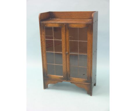 A solid, dark oak dwarf bookcase, single shelf enclosed by a pair of leaded glazed doors, 2ft. - one glass pane cracked