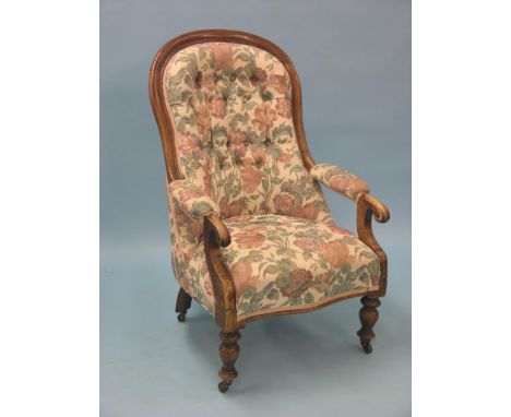 A Victorian mahogany-framed spoon-back elbow chair, on front turned legs with casters, buttoned upholstery matching previous 