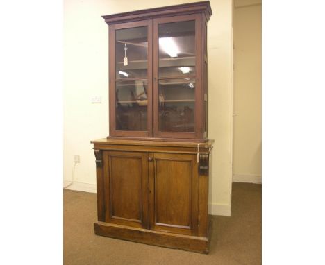 A Victorian tall bookcase, (marriage), panelled mahogany cupboard base with carved corbels, stained pine shelf unit with four