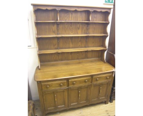 An Ercol dresser, Lavenham, Golden Dawn colour, three-shelf plate rack above panelled cupboard base with three drawers, 4ft. 