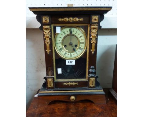 An antique ornate American stained wood and metal detailed cased shelf clock with visible pendulum and gong striking movement