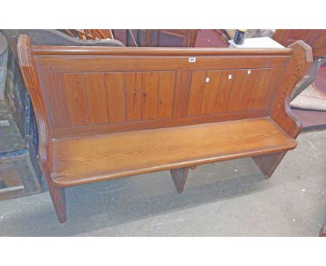 A 1.48m late Victorian pitch pine church pew with panelled back and shelf to rear, flanking wide brass drop handles and shape