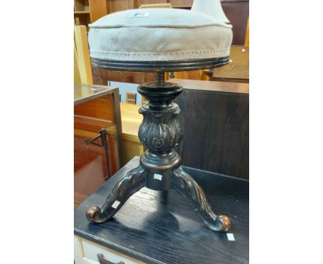 A late Victorian carved mahogany piano stool with adjustable screw action and upholstered seat, set on acanthus pillar and tr