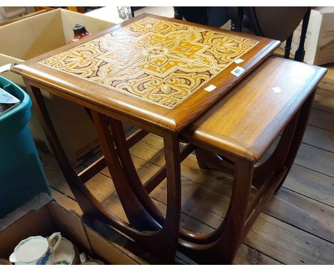 A harlequin nest of three retro teak tea tables, the largest with tile inset top, all set on shaped standard ends