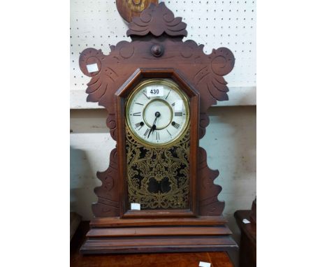 An American stained wood cased 'gingerbread' shelf clock with decorative glazed panel door and New Haven Clock Co. gong strik