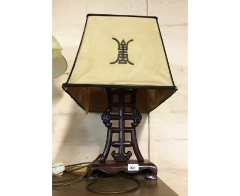 A 20th Century Chinese carved hardwood lamp of pierced symbol form with original shade - one leg a/f and liner to shade torn