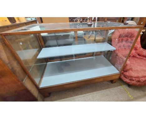 A 1.22m vintage commercial shop display counter with oak beaded glazing and material lined shelves enclosed by glazed sliding