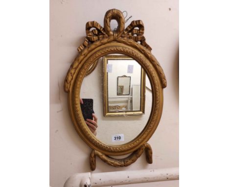 A small vintage Georgian style ornate gilt framed wall mirror with bow pediment and oval plate