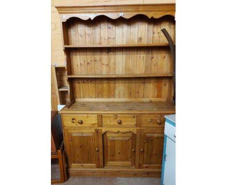 A 1.37m modern pine two part dresser with two shelf open plate rack over a base with three frieze drawers and triple panelled