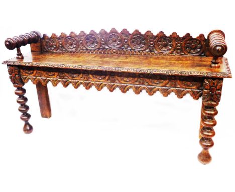 A 1.2m 19th Century carved oak window seat with decorative back rail, solid seat and flanking armrests, set on bobbin turned 