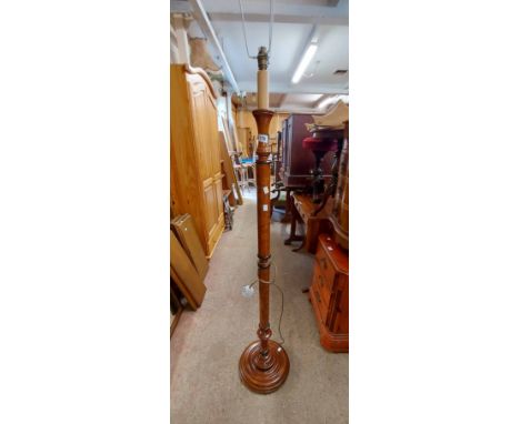 A reproduction wood grained and ebonised lined standard lamp with turned pillar and moulded circular base
