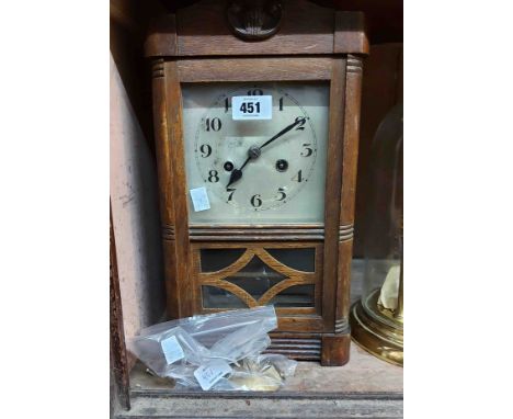 A vintage oak cased mantel clock with visible pendulum and eight day gong striking movement