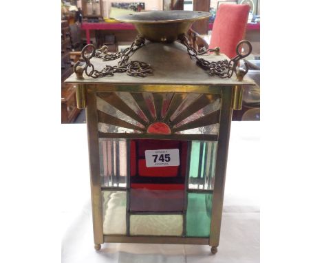 An early 20th Century brass framed hall lantern with leaded textured glass panels and an Art Deco sunburst motif, with hangin