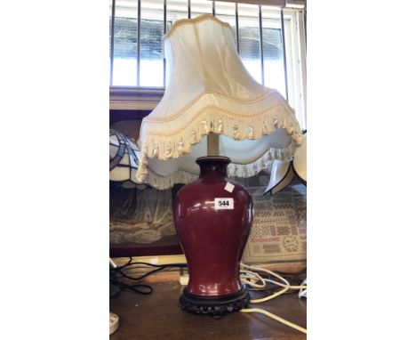 A modern Chinese porcelain table lamp of shouldered baluster form with sang de bouef glaze effect, set on carved hardwood bas