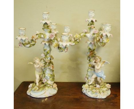 Pair of Dresden three branch porcelain candelabra decorated with cherubs and having allover floral encrusted decoration, the 