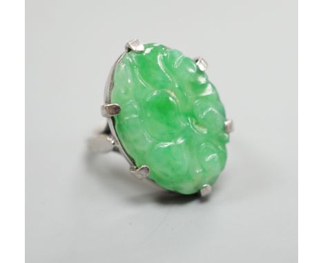 A white metal and oval jade set ring, carved with fruit, size F, gross weight 6.3 grams.