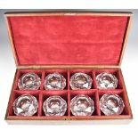 A set of eight faceted cut glass table salts with star cut bases, in fitted oak case.