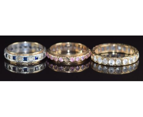 Three 9ct gold eternity rings, one set with pink sapphires (missing stone), one sapphires and spinel and the other spinel, 8.