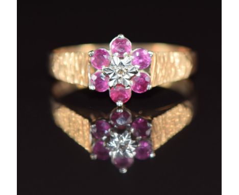 A 9ct gold ring set with a diamond surrounded by rubies, 1.8g, size M